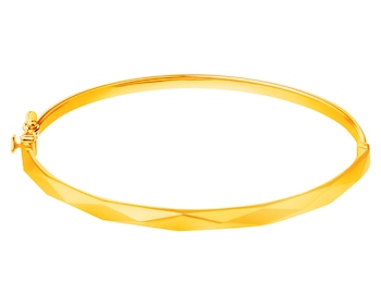 A gold stiff bracelet with a clasp